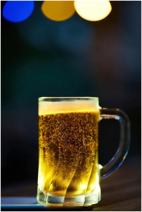 A glass mug of cold beer with frothy head and boke