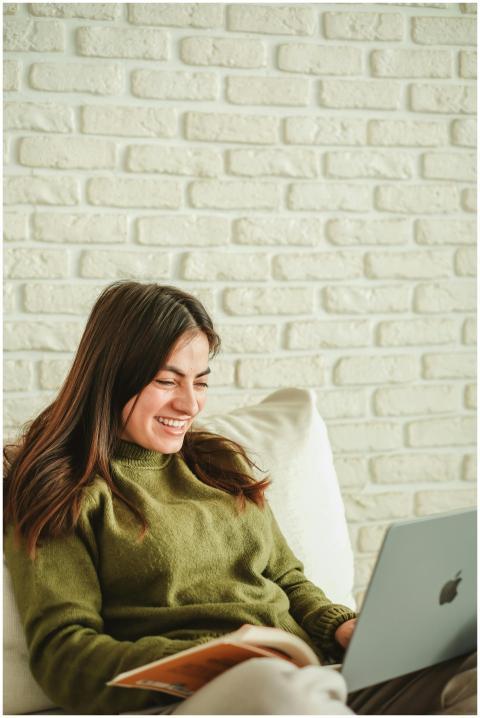 Smiling young woman using a laptop and reading a b