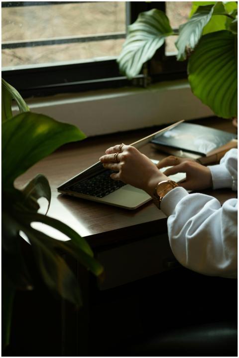 A woman working remotely on a laptop by a window,