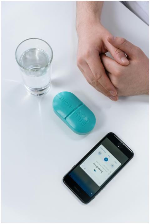 A health app, pill box, and water glass display mo