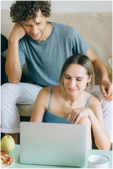 A couple sitting on a sofa browsing a laptop, show