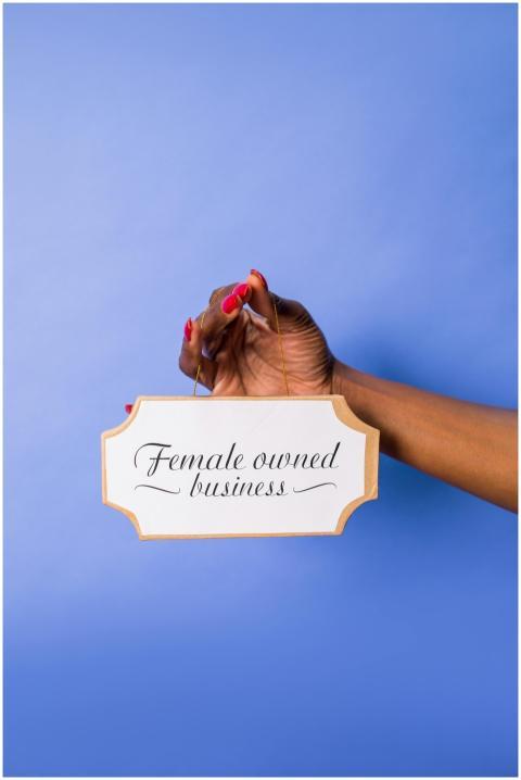 Hand holding a sign stating 'Female owned business