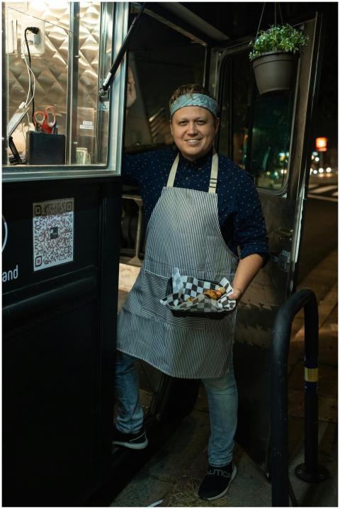 A smiling food truck vendor serving delicious stre