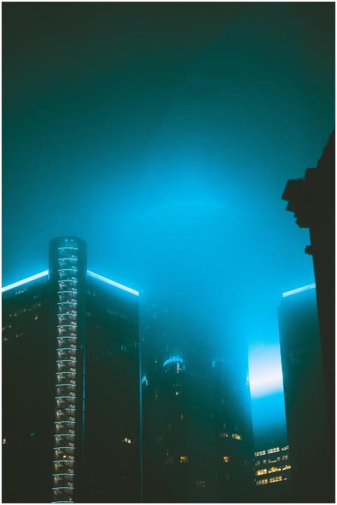 Tall buildings in a misty urban setting, illuminat