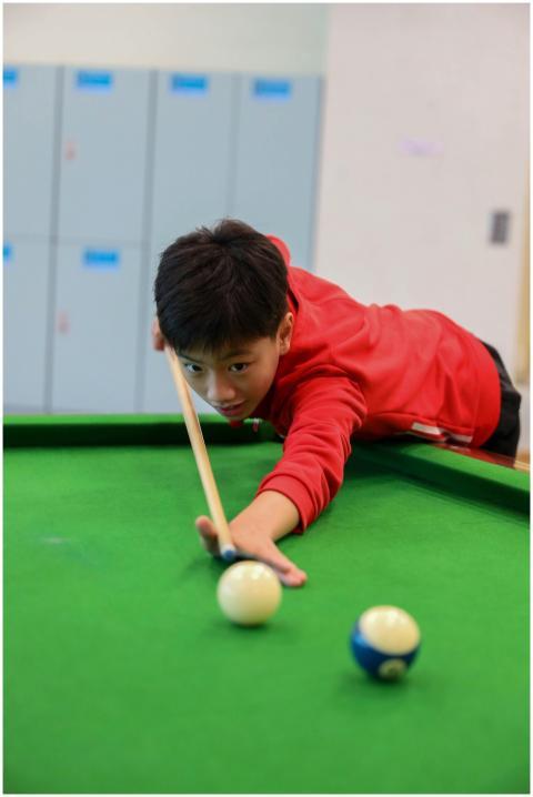 A young boy in red shirt aims carefully at a snook