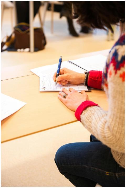 A woman writing notes in a notebook during a class