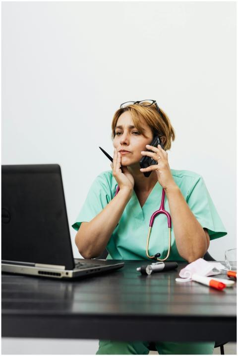 Doctor in green scrubs working remotely, using lap