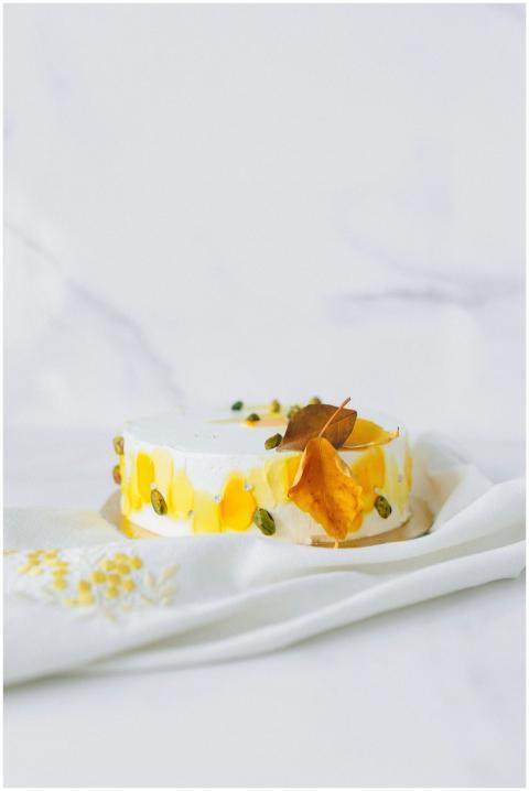 A stylish cake with pistachio and mango accents, p