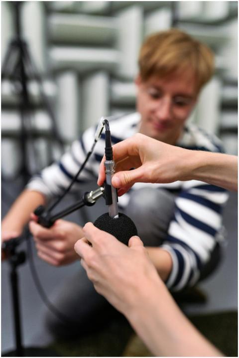A sound engineer carefully adjusts a microphone in