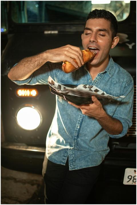A young man savoring a delicious snack from a food