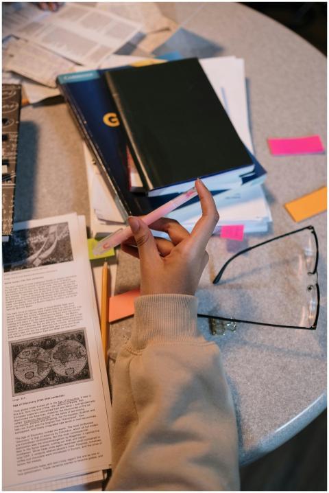 A student holding a pen surrounded by books and no