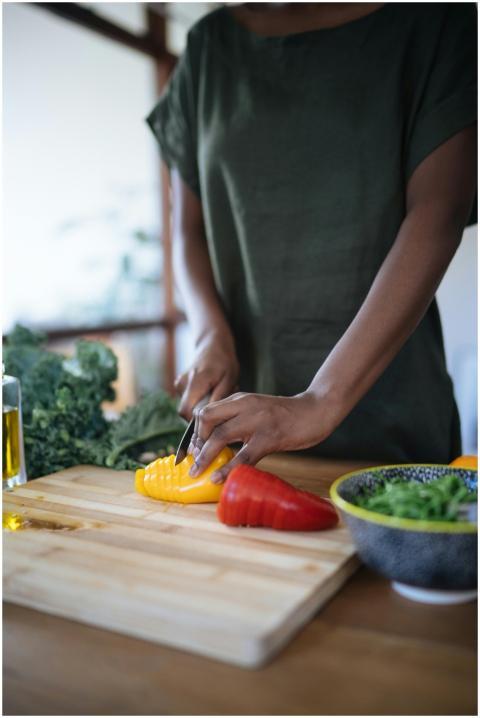 A person slicing colorful bell peppers on a wooden