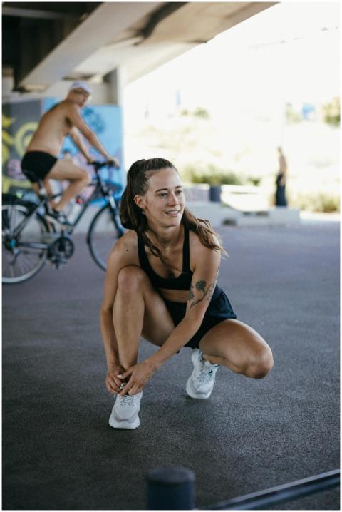 Smiling woman in active wear tying her laces outdo