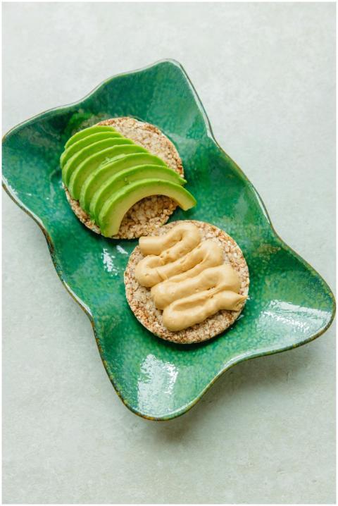Sliced avocado and hummus on rice cakes served on