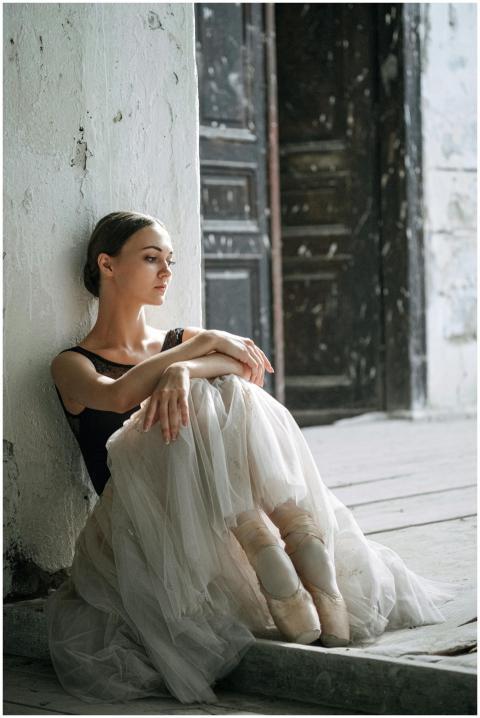 A serene ballerina in pointe shoes sits gracefully