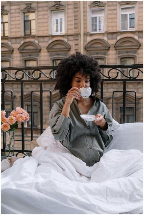 Pregnant woman sipping coffee on a cozy balcony, s