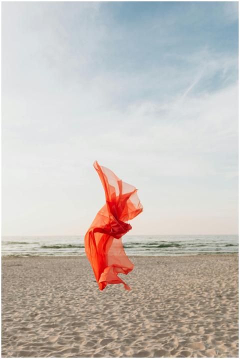 A vibrant red fabric floats on Karwia Beach, captu