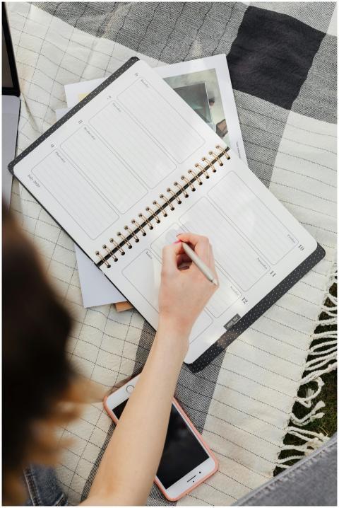 Young woman writing in her planner while enjoying