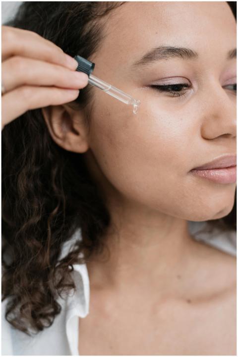 A young woman applying skincare serum to her face