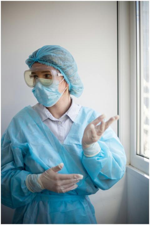 A healthcare professional wearing PPE stands indoo