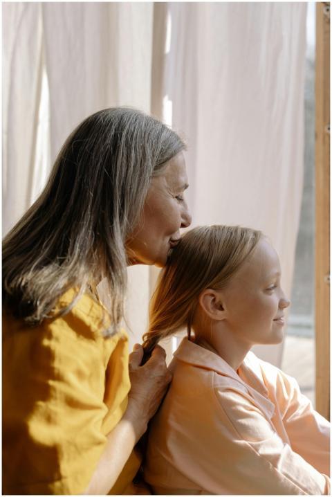 Elderly woman lovingly braiding young girl's hair