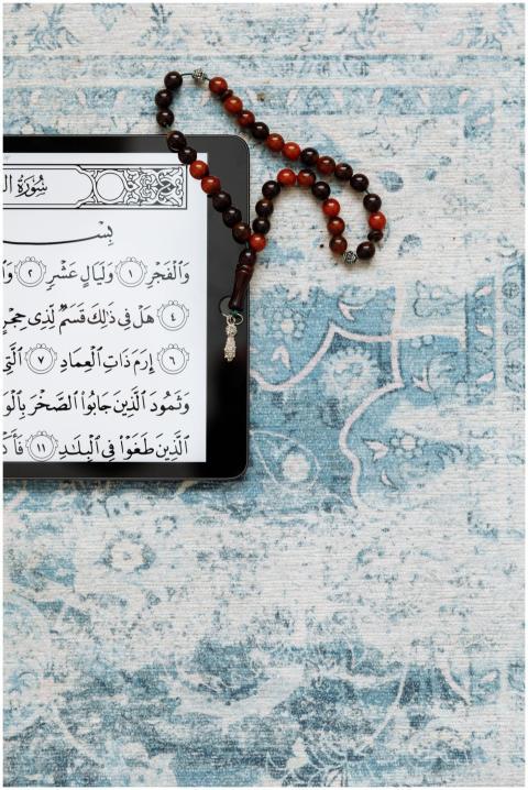 A tablet displaying the Quran on a prayer rug with