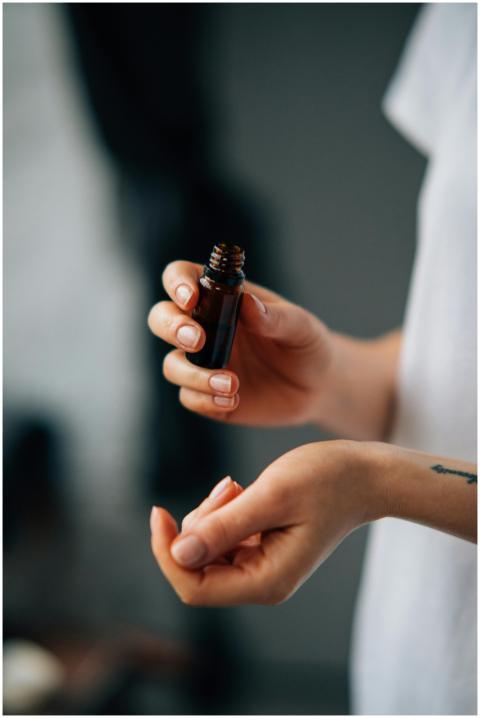 Hands applying essential oil from a small bottle.