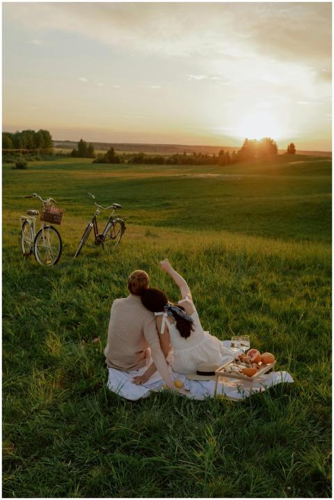 A couple enjoys a picnic during sunset, sitting on