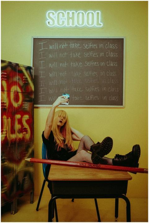 Teenage girl taking a selfie in classroom, defying