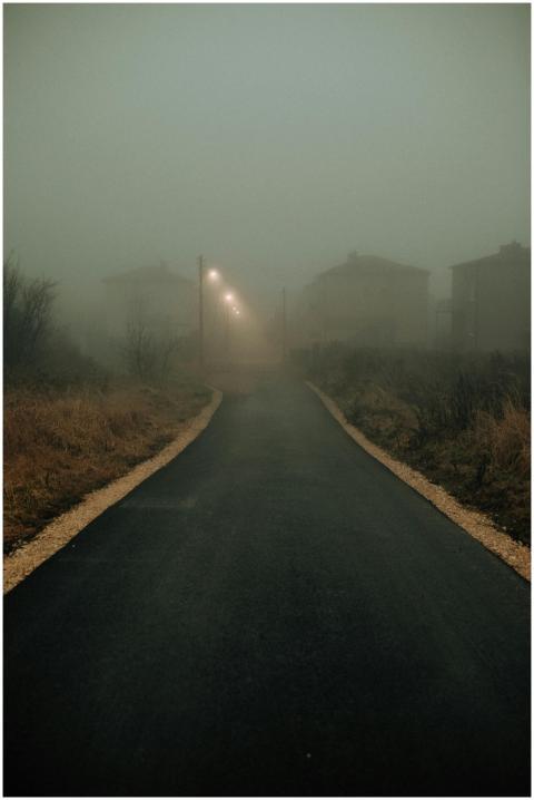 A foggy nighttime street view with illuminated str