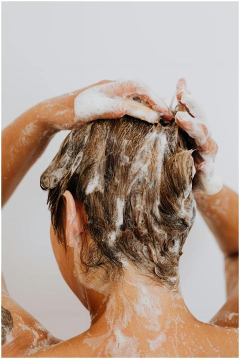 Close-up of a woman washing hair with foam shampoo