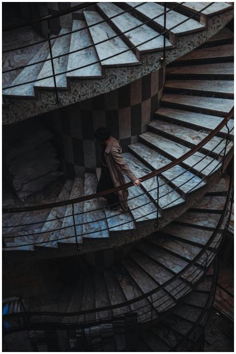 A person walks down a dramatic spiral staircase in