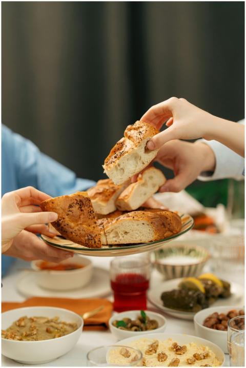 Hands reaching for bread at a festive table settin