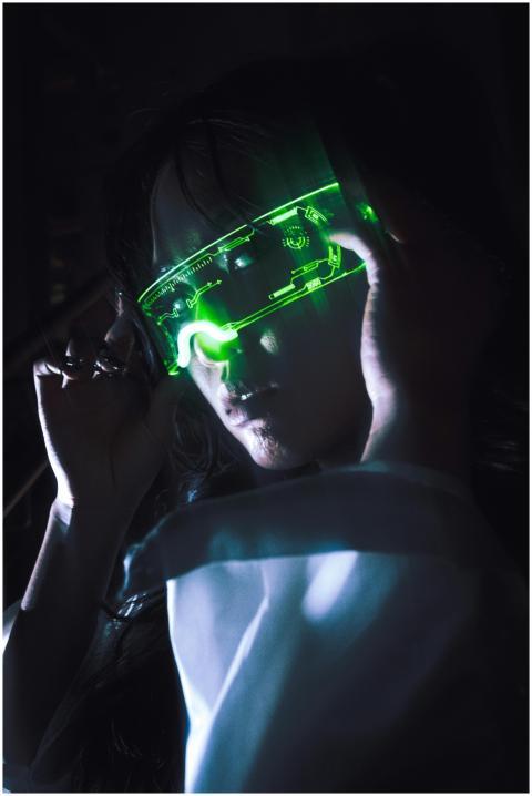 A woman wearing illuminated green neon glasses, cr
