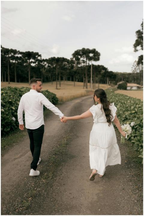 A couple walks hand in hand on a scenic country ro