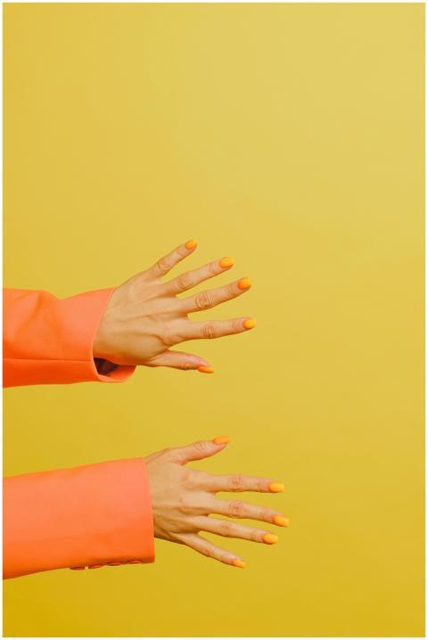 Stylish orange manicured hands in orange sleeves o