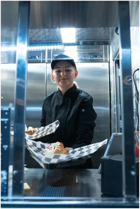 A chef in a food truck serving appetizing street f