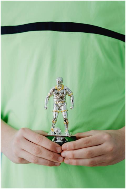 A child proudly holding a silver soccer trophy in