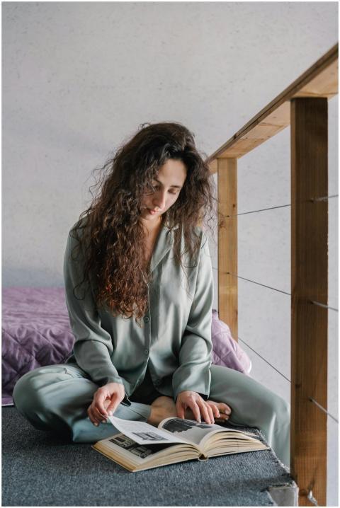 Woman sitting on floor in cozy pajamas, reading a