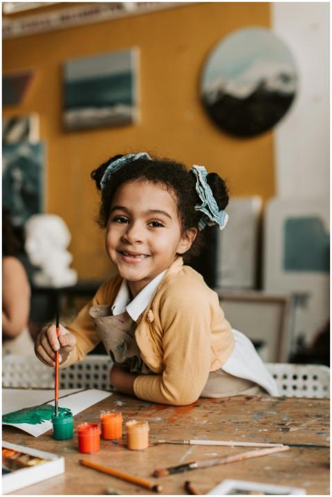 Smiling child painting in an art classroom surroun