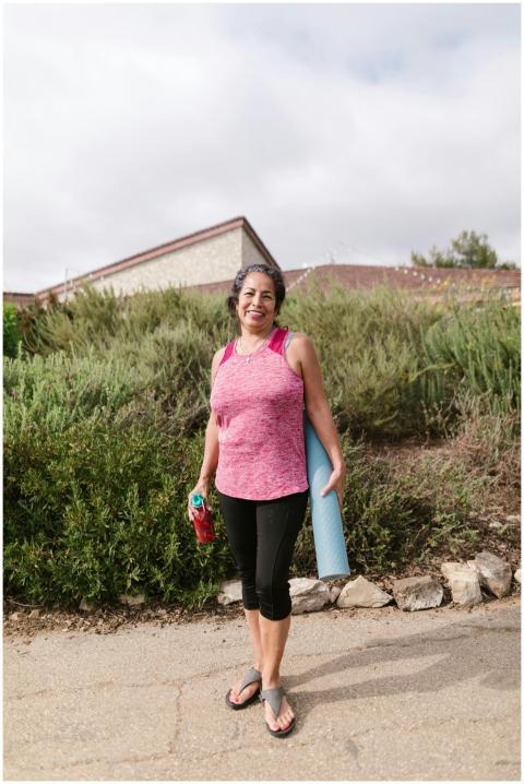 A senior woman smiling while holding a yoga mat an