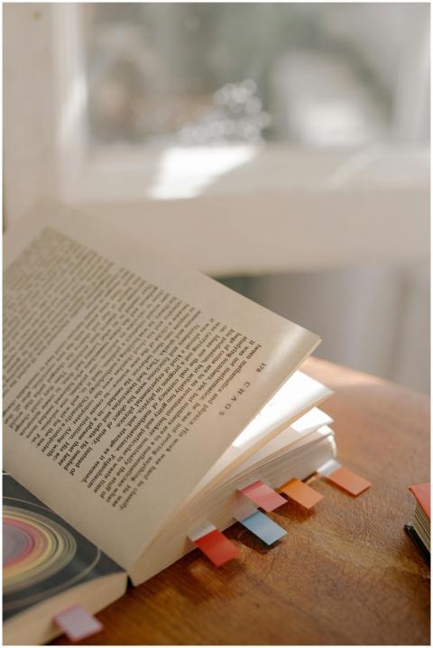 Open book with vibrant bookmarks, basking in warm