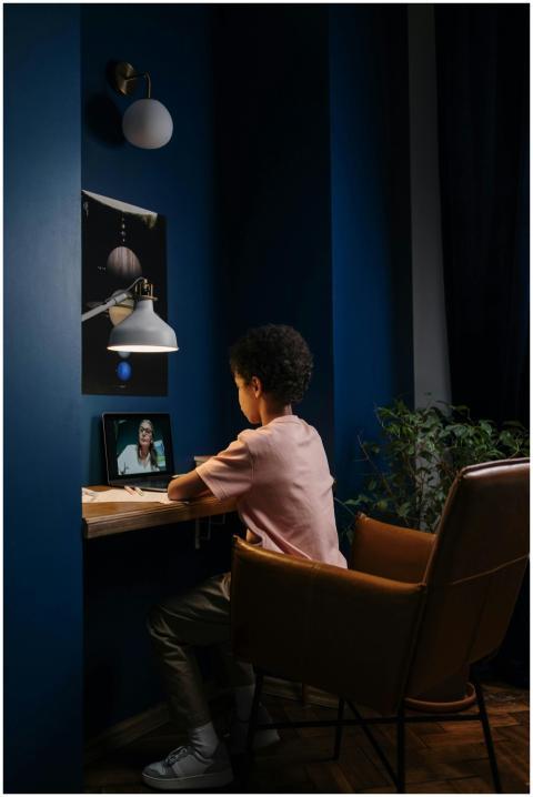 Child studying online at a desk, illuminated by a