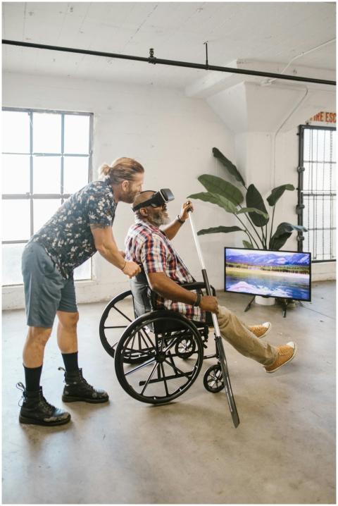 Man assisting another in a wheelchair using a VR h
