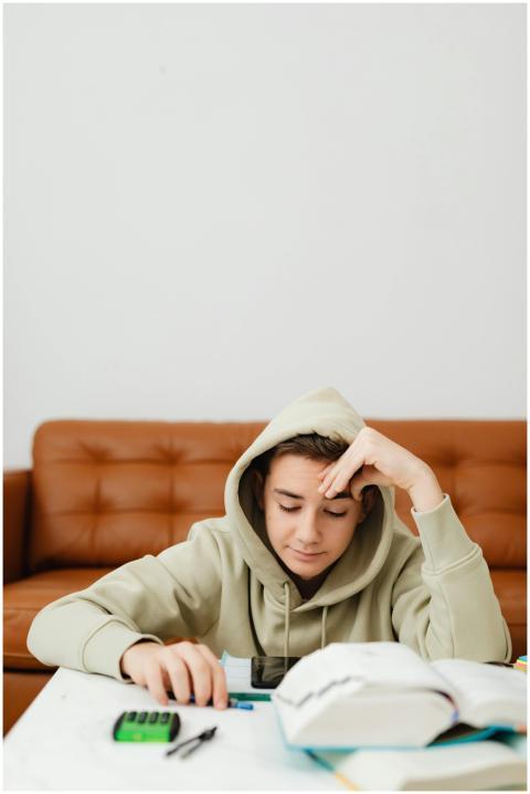 Teenager in a hoodie studying at home with books a