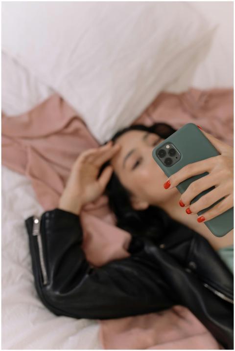 A woman lying on a bed taking a selfie with her sm