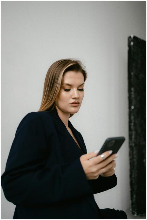 Businesswoman in a blazer using a smartphone indoo