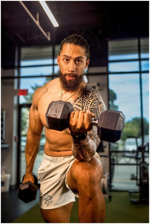 Muscular tattooed man exercising indoors, lifting