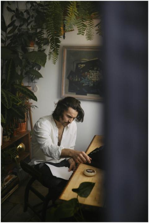 A focused poet writing at a desk surrounded by lus