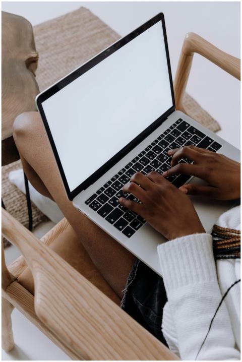A person typing on a laptop while seated in a mode